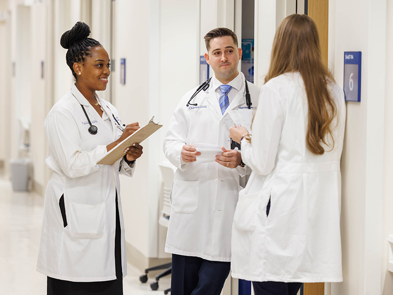 Three medicine residents conversing in hospital hallway
